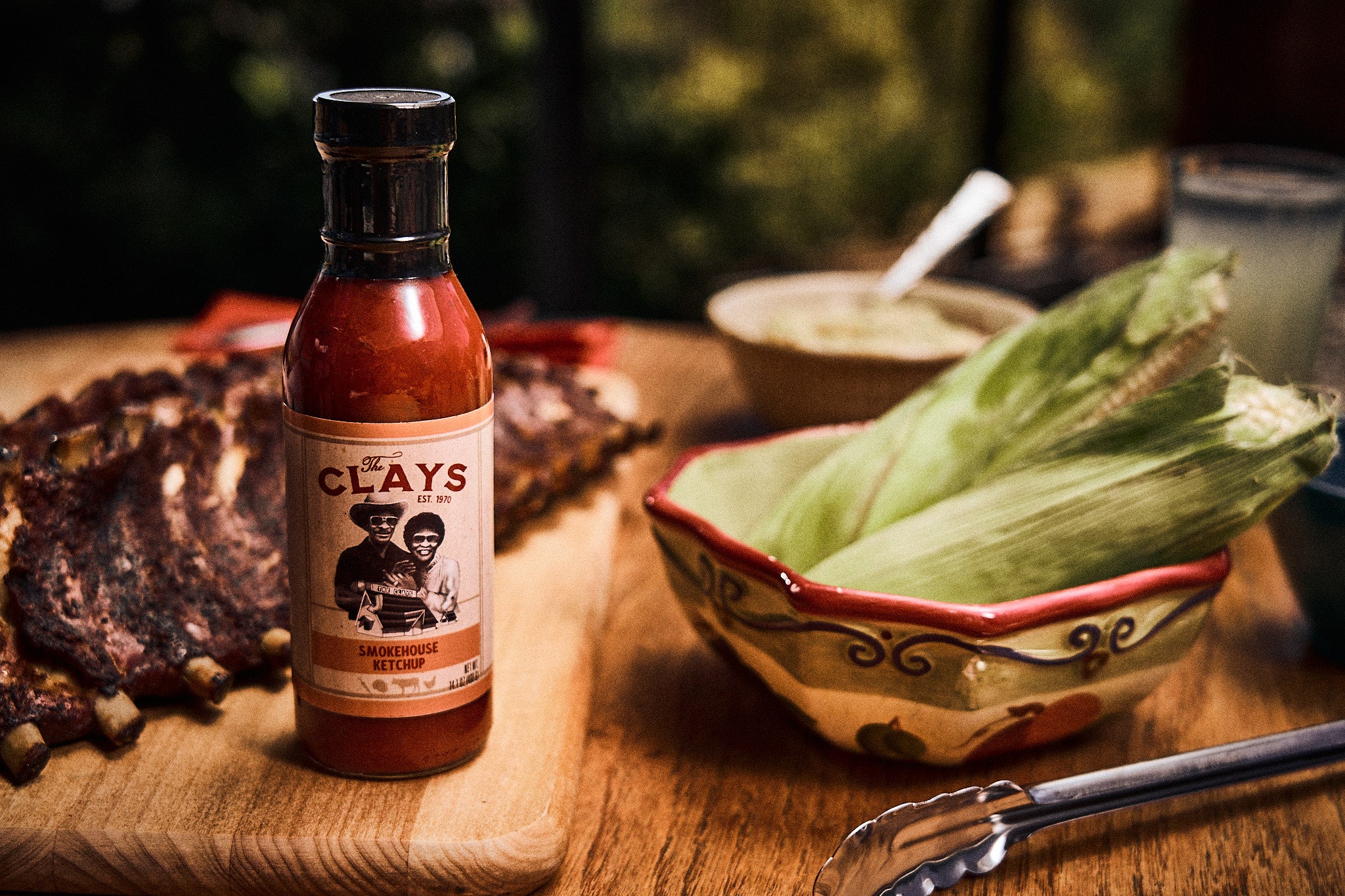 The Clay's Smokehouse Ketchup On A Table With Food