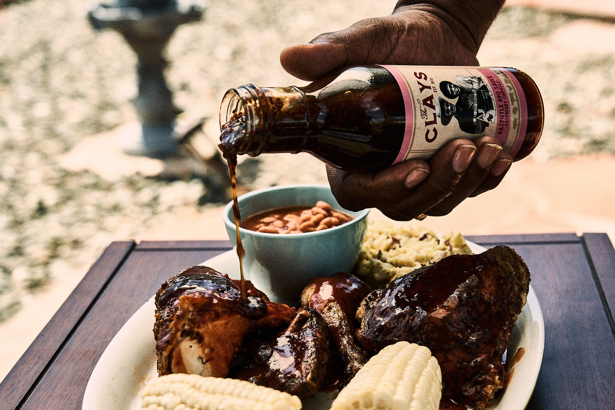 The Clay's Razpotle BBQ Sauce On Table With Food